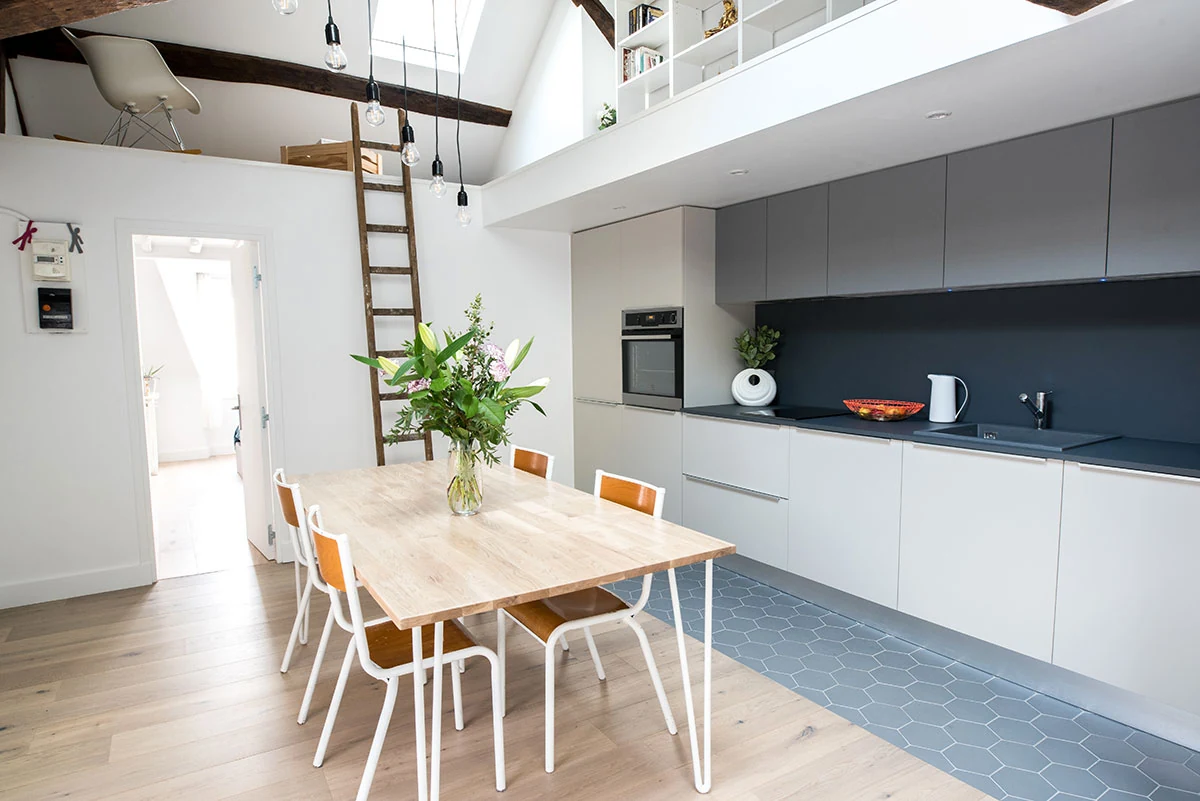 Salle à manger sous charpente apparente dans un duplex rénové à Paris 1er