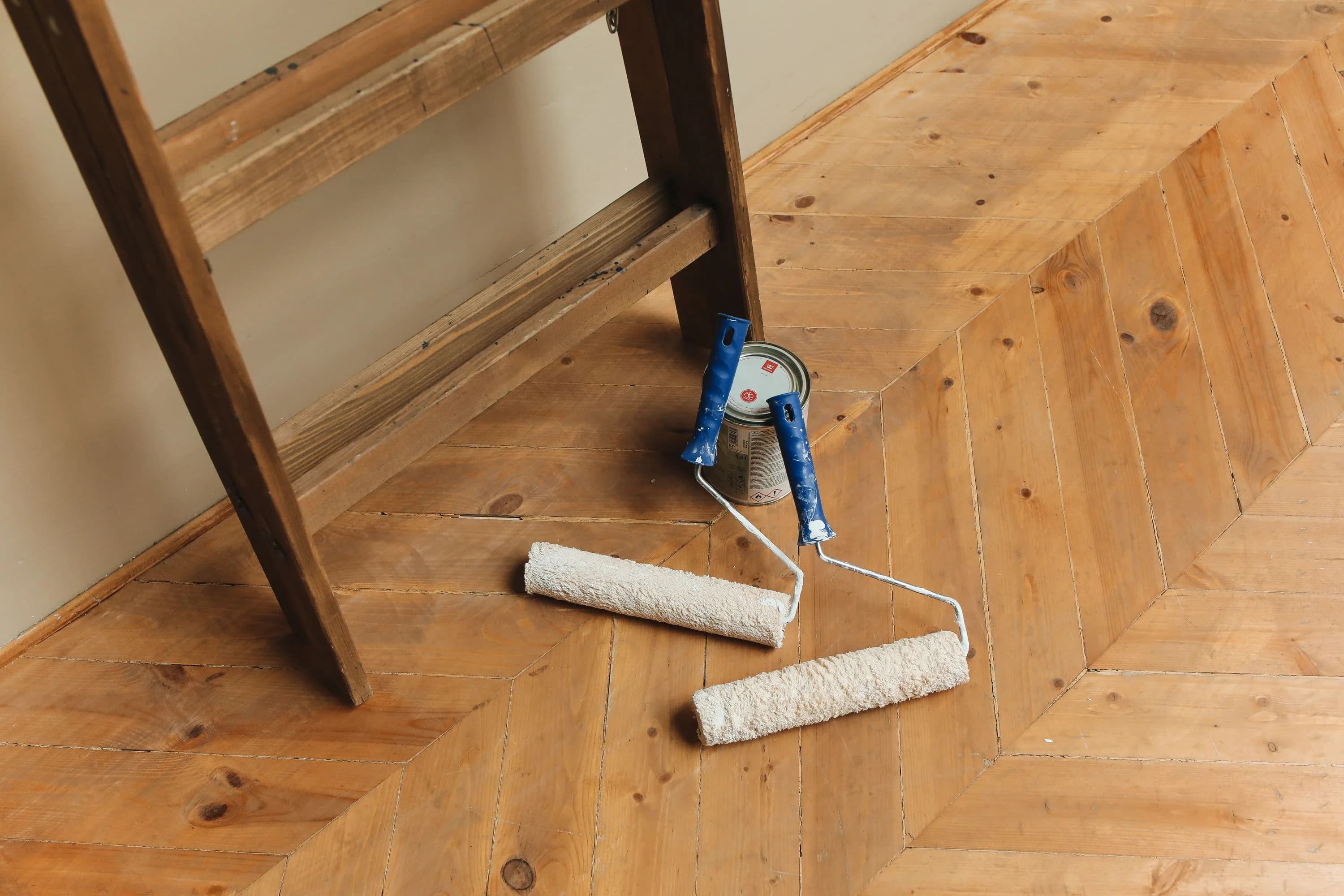 Rouleaux de peinture posés sur un parquet